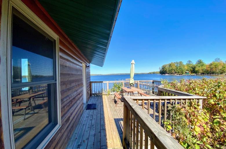 Deck area overlooking the lake and beach with picnic table and charcoal grill.